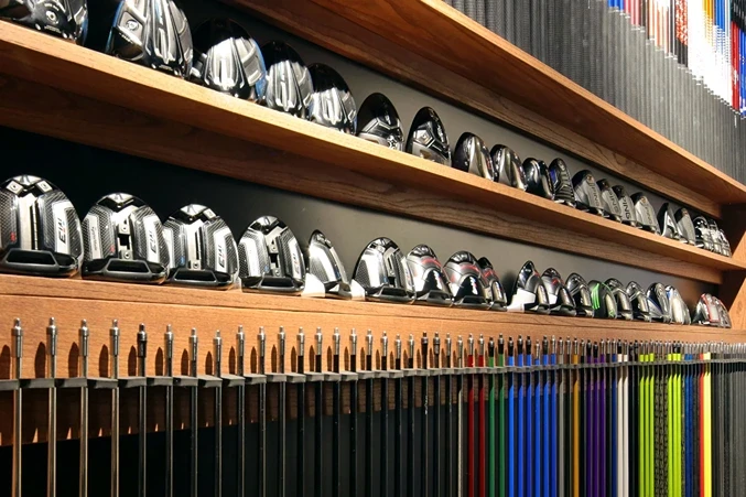 Golf club shafts and driver heads displayed in a professional club fitting studio