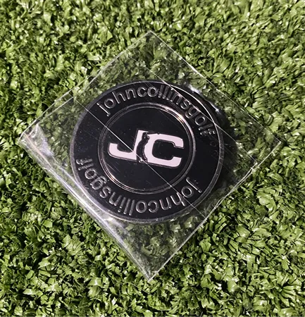 JC Golf Studio black golf ball marker with white JC logo placed on artificial turf in Queensland